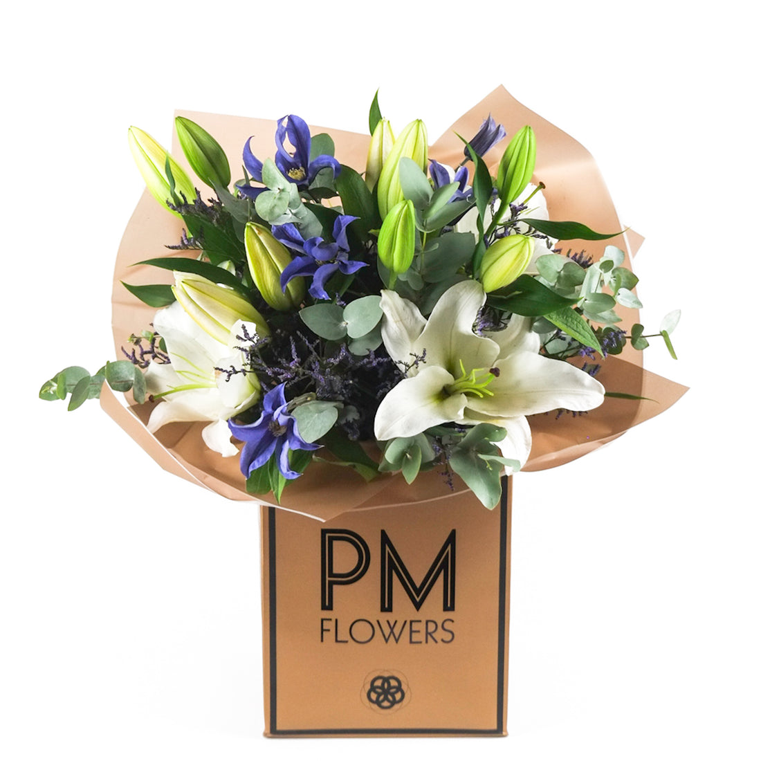 A bouquet of flowers including white lilies, purple-blue clematis, limonium, and eucalyptus, arranged in a beige-colored paper with a PM Flowers branding.
