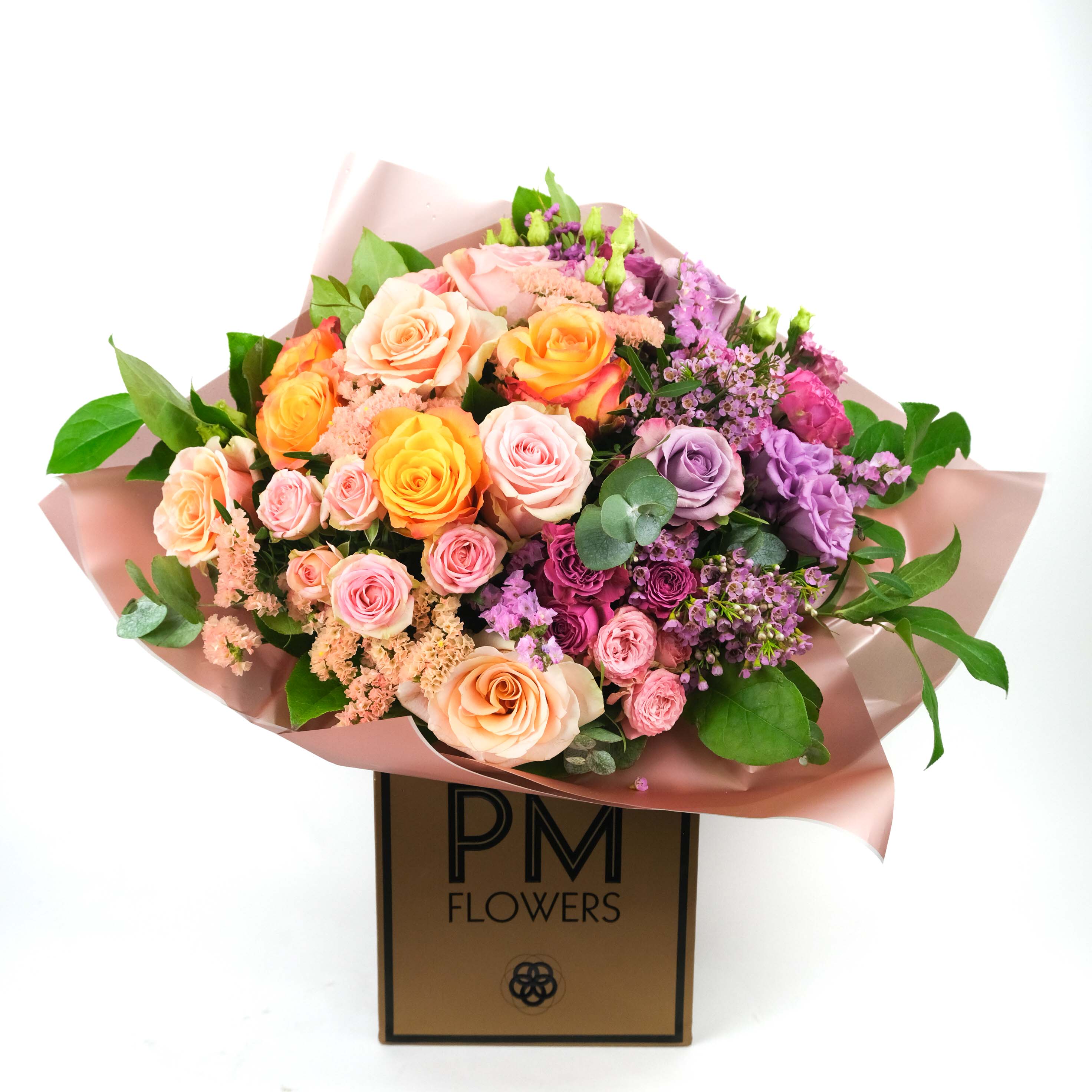 A vibrant bouquet of flowers featuring a mix of purple, pink, and orange blooms, wrapped in a peach-colored paper with &