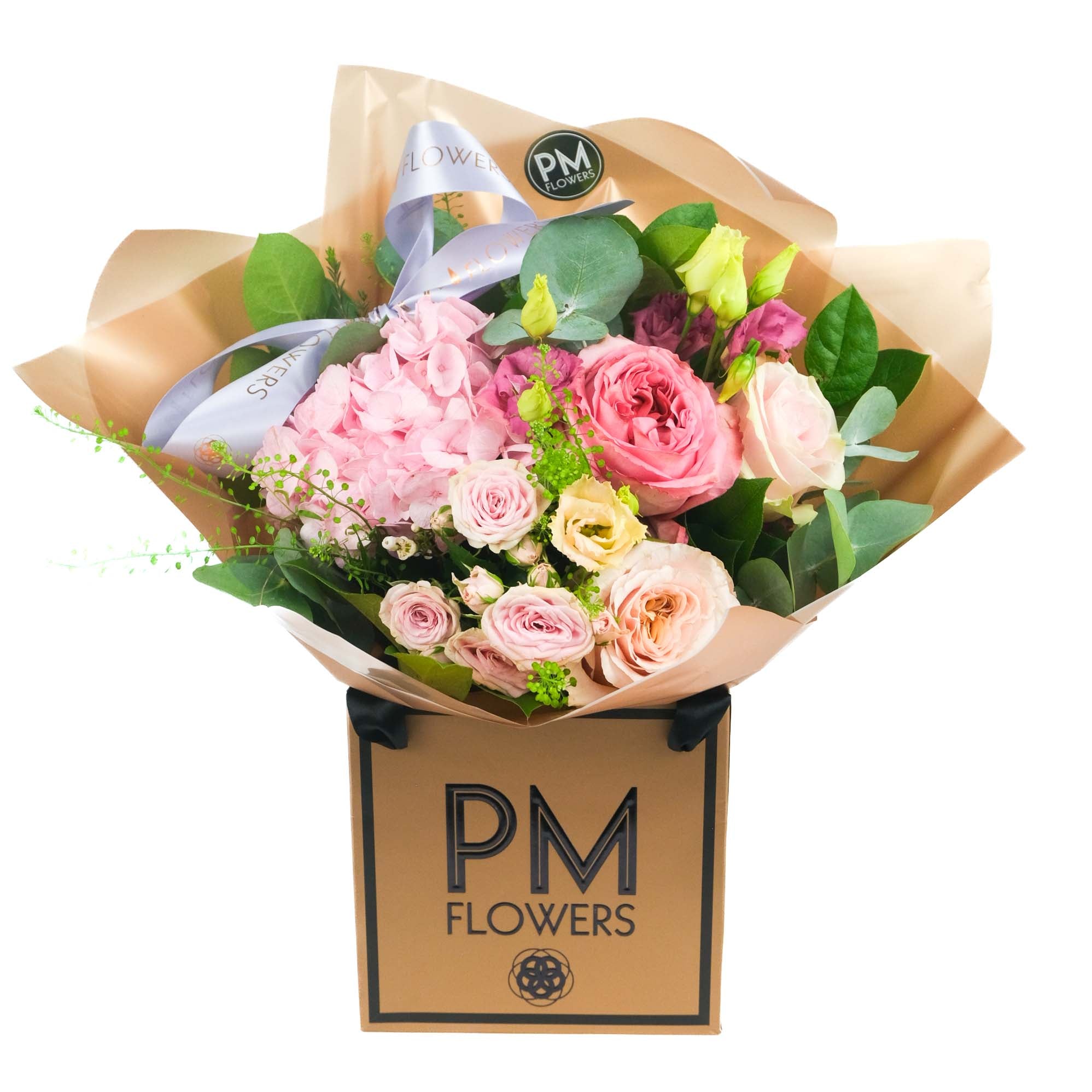 A bouquet of pink and peach flowers including roses and hydrangea, wrapped in a brown paper with a label that reads &