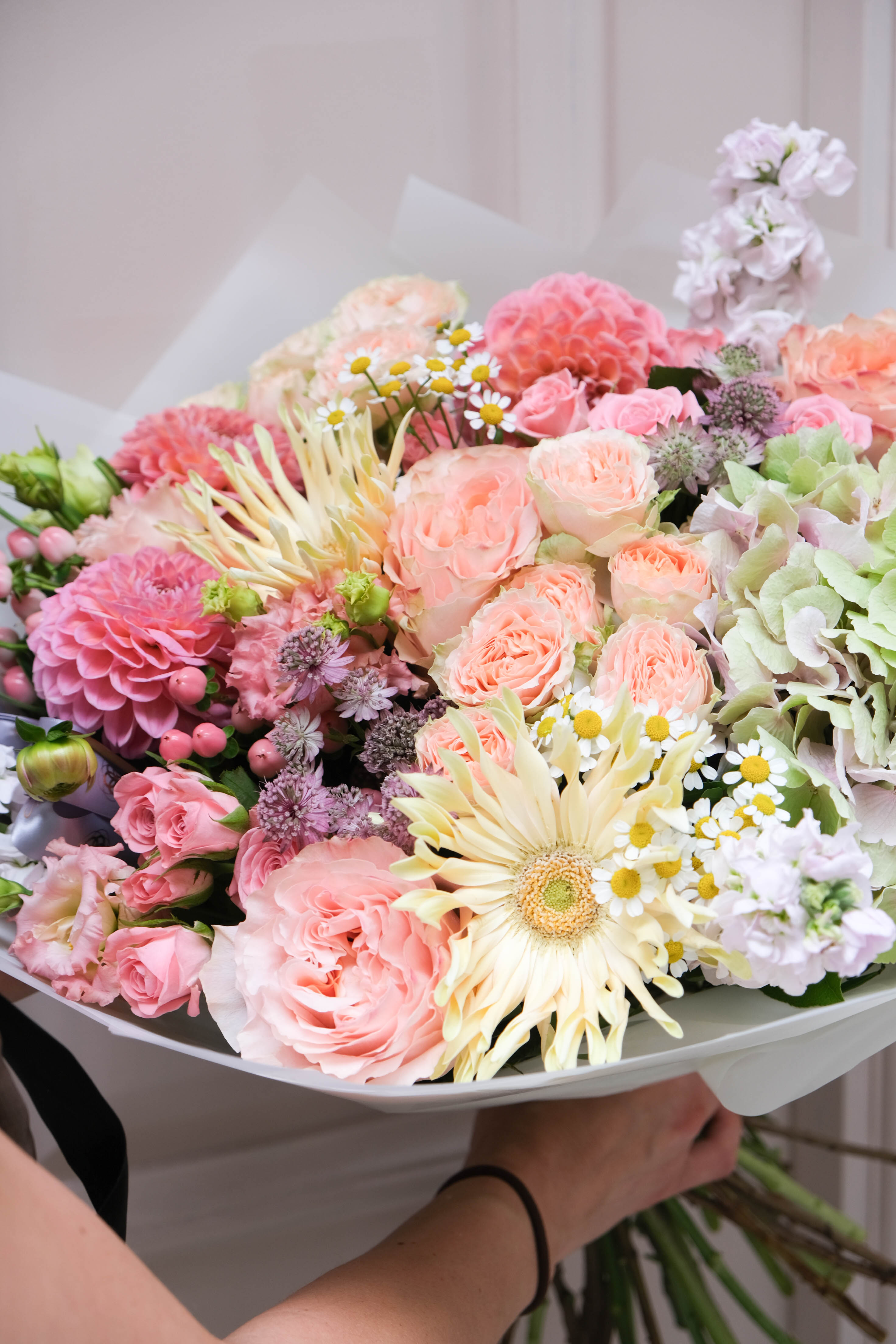 Bouquet of colorful flowers held by a person against a neutral background