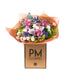 A vibrant bouquet of assorted flowers including pink cymbidiums, blush pink lisianthus, and white spray roses, presented in a box with the branding &