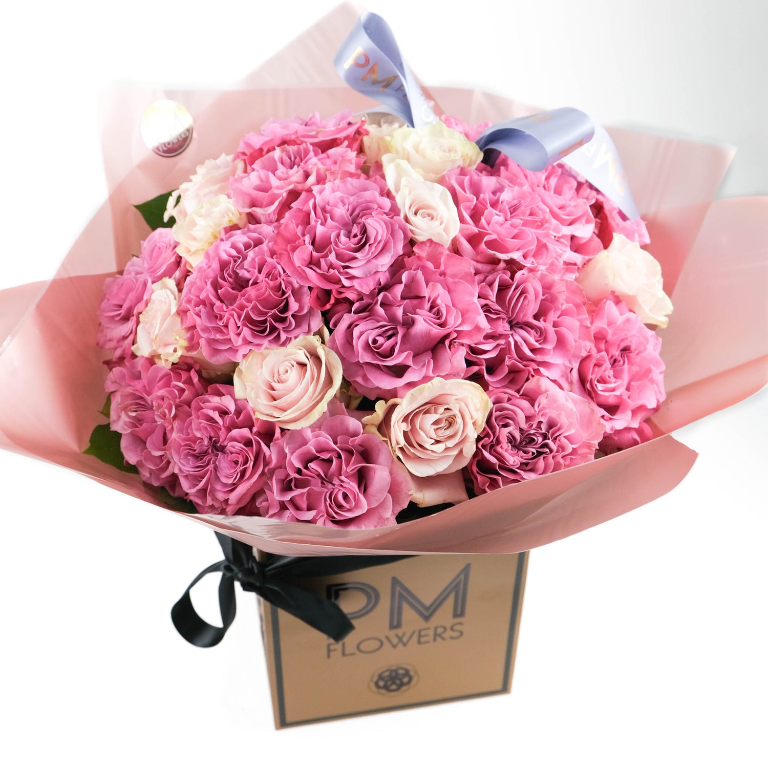 A bouquet of pink roses with cerise fluffy roses and light pink roses, arranged in a box with a ribbon.