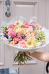 Bouquet of flowers held in front of a pastel door
